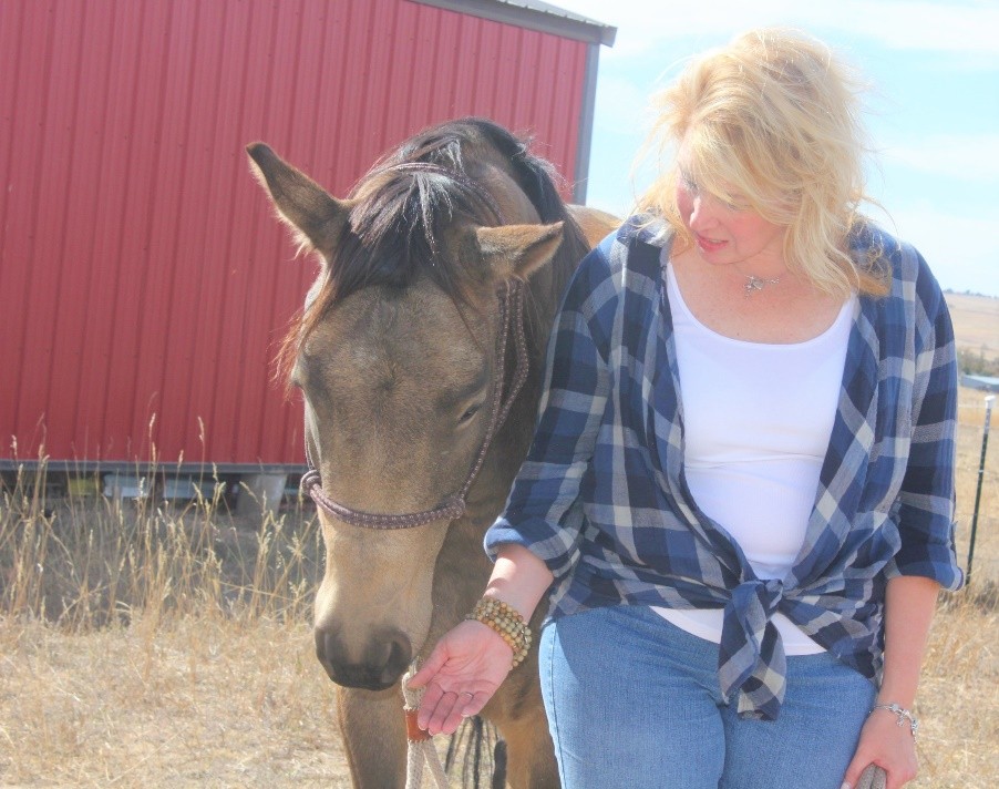 A woman stands beside a horse