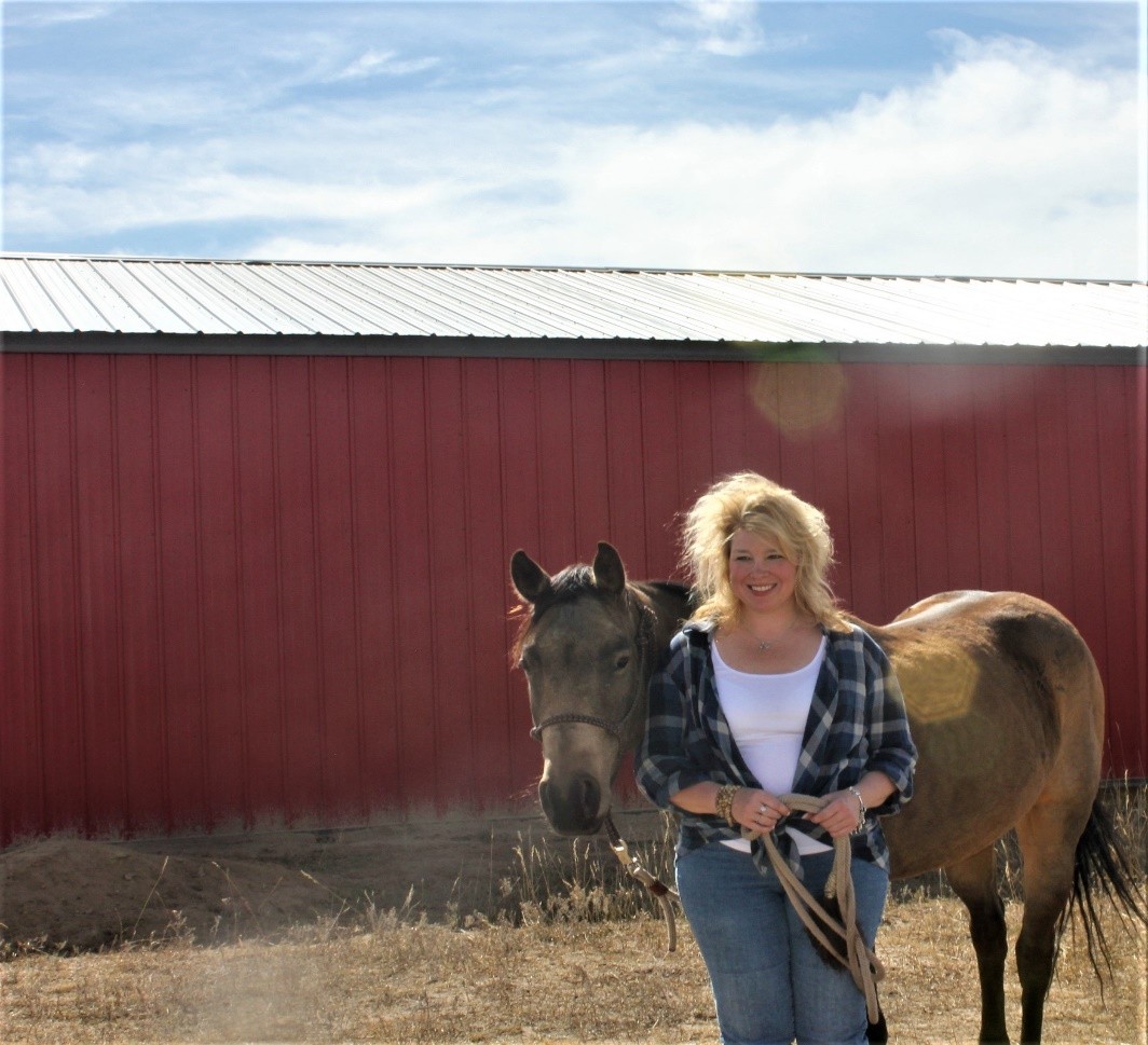 A woman stands beside a horse